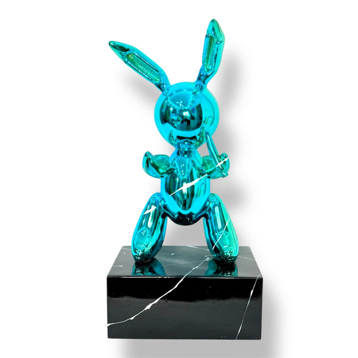 Turquoise balloon rabbit sculpture on a black marble base against a white background